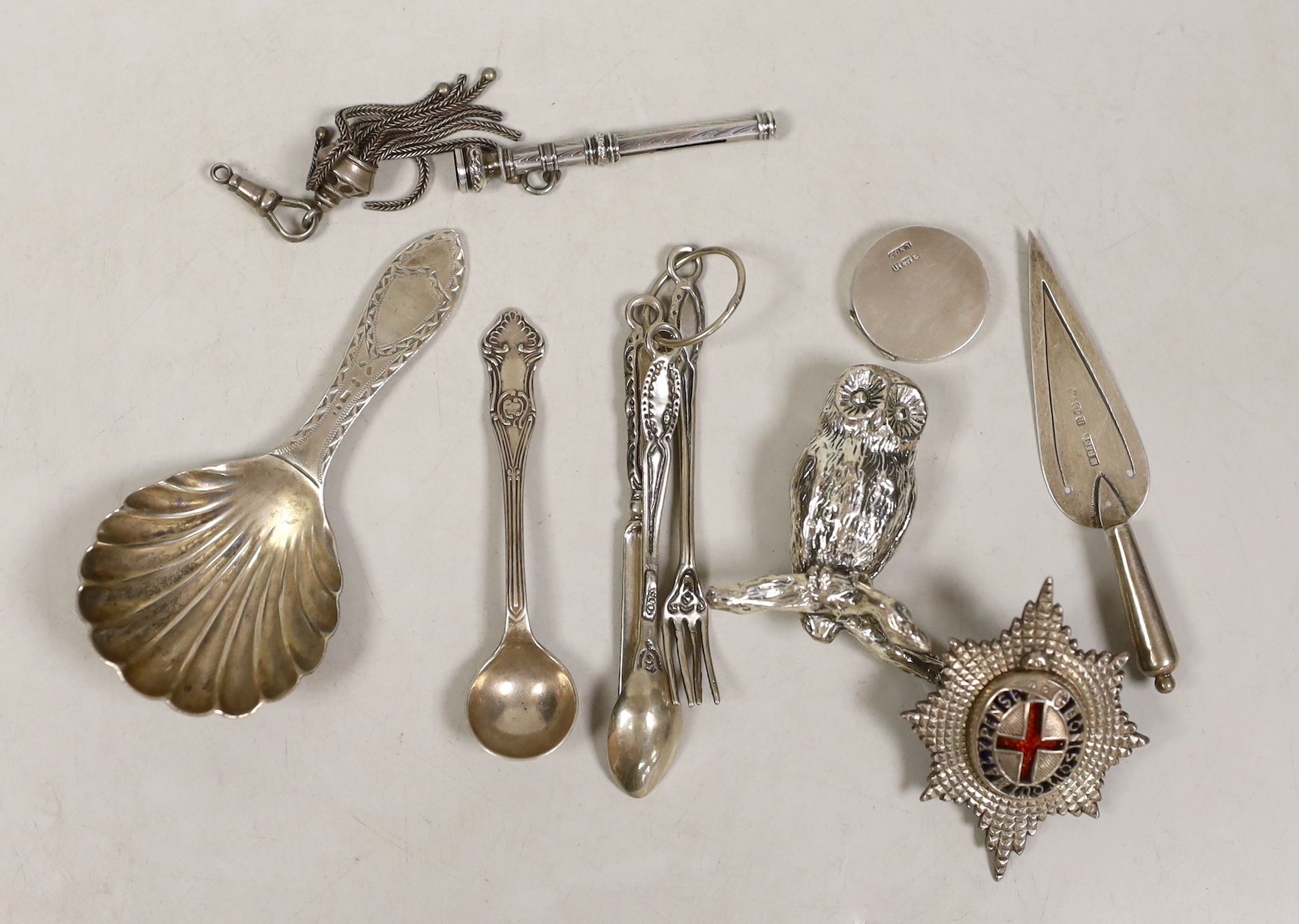 Sundry small silver etc, including a George V silver caddy spoon, a white metal badge, small cutlery and a plated owl.
